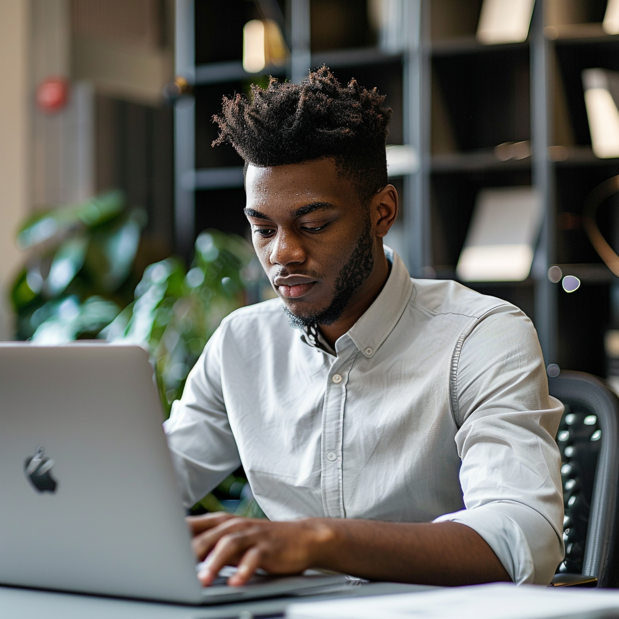 man-sits-table-with-laptop-black-apple-logo-it